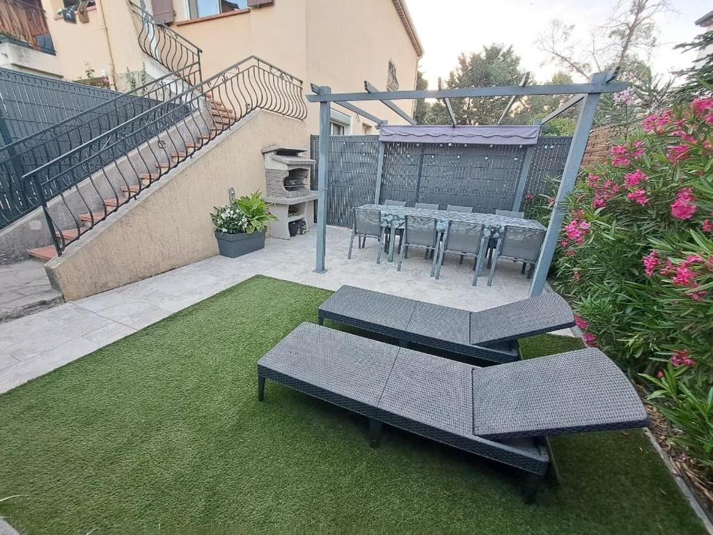 patio ze stołem i krzesłami na trawie w obiekcie La Villa Castel - Haut de villa - parkings- 3 chambres - 8 couchages - jardin - barbecue w Cagnes-sur-Mer