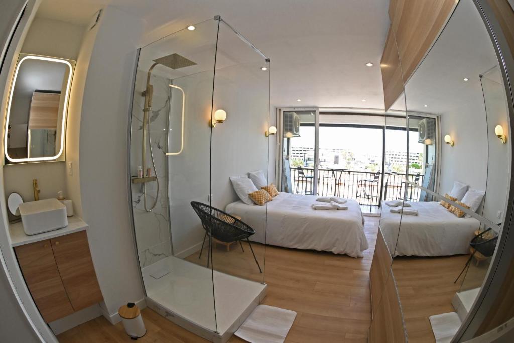 Cette chambre comprend un lit, une douche et un miroir. dans l'établissement Studio B Heliopolis FGH, au Cap d'Agde
