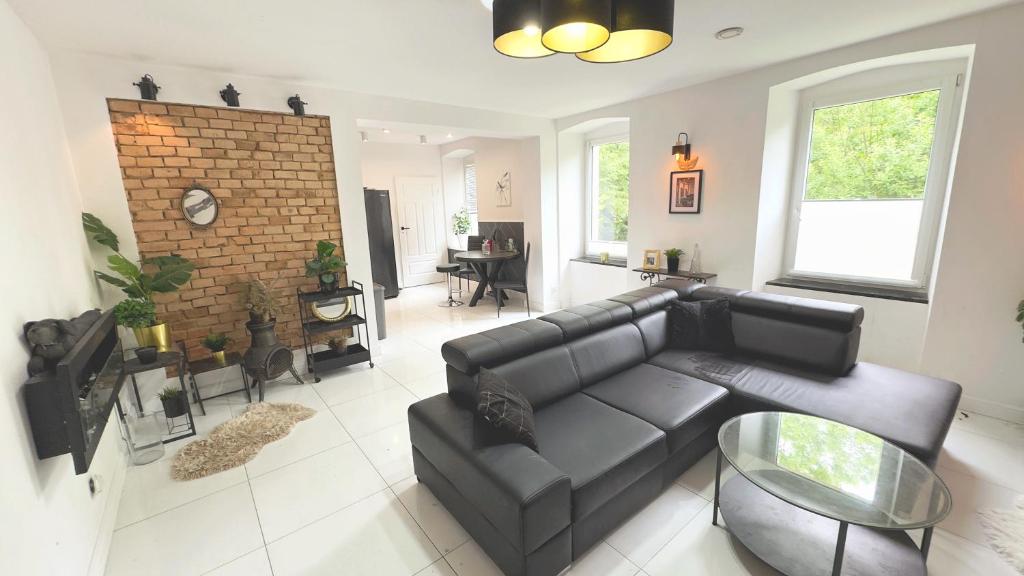 a living room with a black couch and a fireplace at Stylowy Apartament w sercu Uzdrowiska in Jedlina-Zdrój