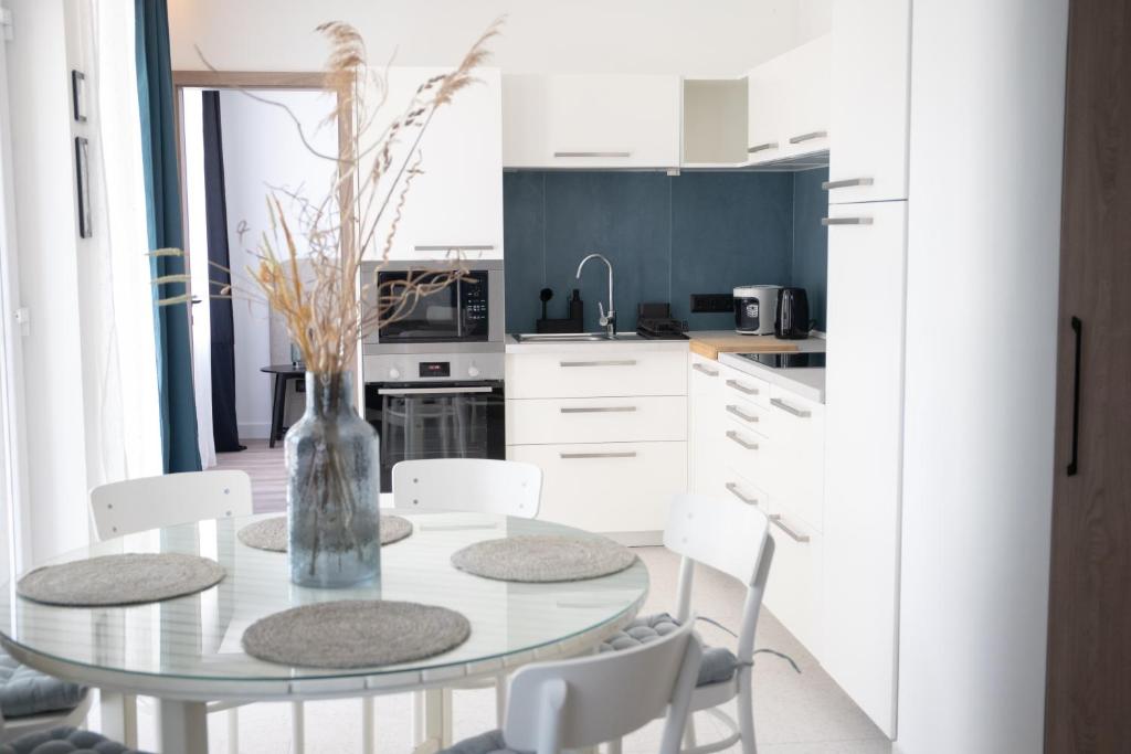 a kitchen with a glass table and white chairs at Naluri Apartman II in Balatonboglár