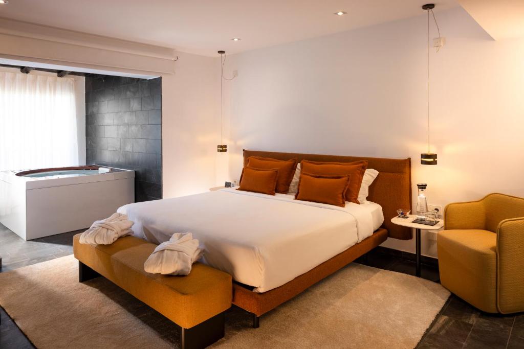 a bedroom with a large bed and a chair at Hotel Boutique Ses Pitreras in San Antonio Bay