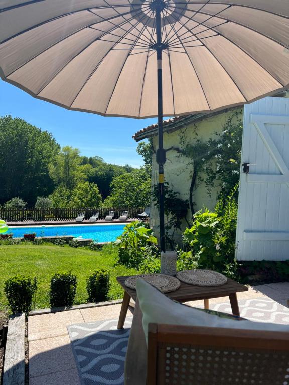 a table with an umbrella next to a pool at La Colline de Tilleul - De La Colline 4 STAR RATED - Beautiful Cottage Near Aubeterre in Saint-Romain