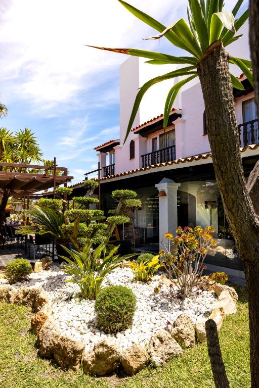 a garden in front of a building with a palm tree at Hotel Boutique Ses Pitreras in San Antonio Bay