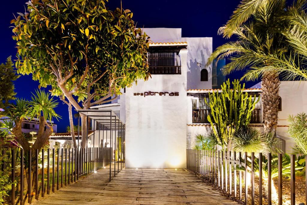 a white house with a fence and palm trees at Hotel Boutique Ses Pitreras in San Antonio Bay