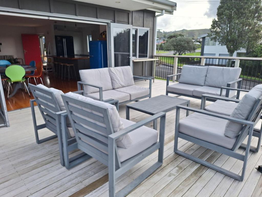 a group of chairs and tables on a deck at The Beach Bach in Waihi Beach