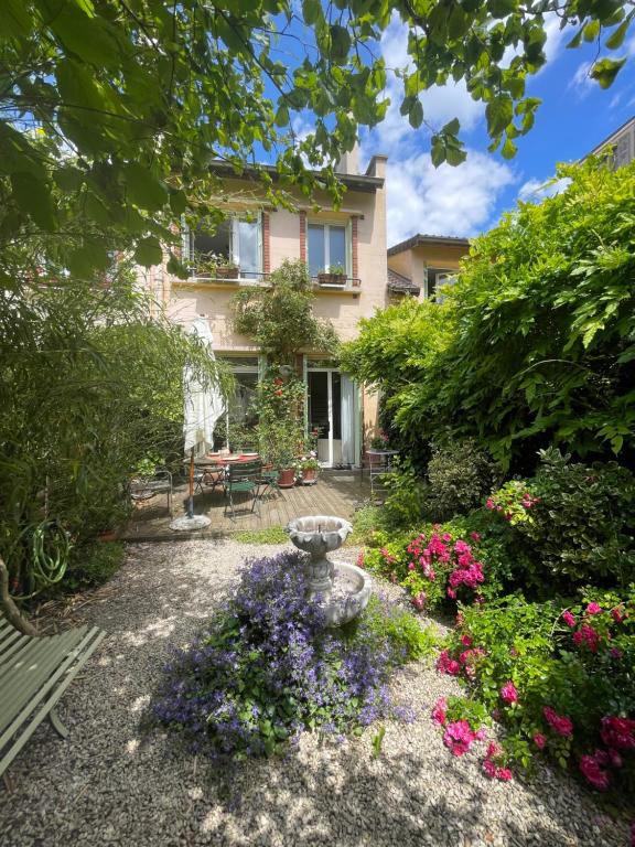 un jardin avec un bain d'oiseaux en face d'une maison dans l'établissement Maison familiale - 20 mn Centre Paris et Stade de France- 5 Chambres, à Saint-Ouen