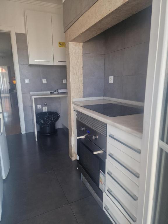 a kitchen with white cabinets and a counter top at D&N Hospedagem Lisboa in Lisbon
