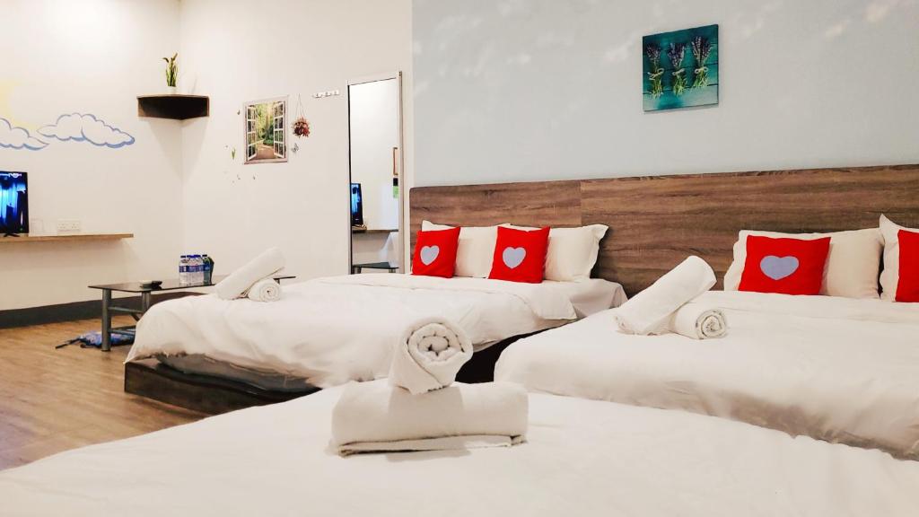 a hotel room with three beds with red pillows at Winggarden Murals House by JE Boutique Guesthouse in Ipoh