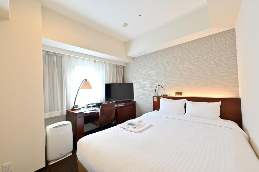 a hotel room with a large bed and a desk at Hotel Keihan Sapporo in Sapporo