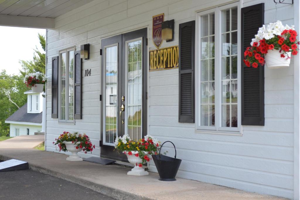 a building with flowers in vases outside of it at Hôtel Maison Blanche in New Carlisle