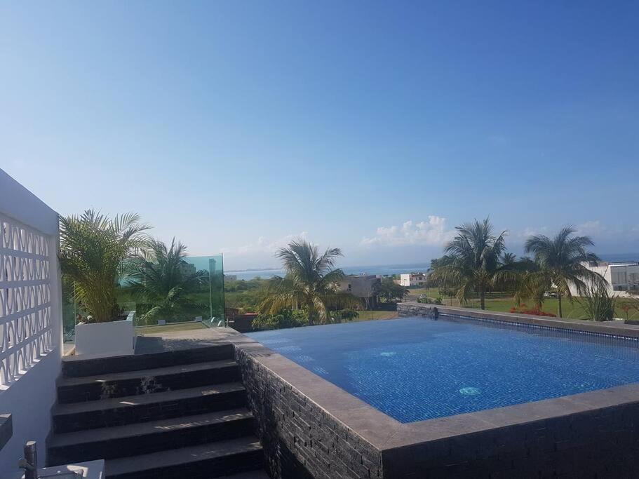 a swimming pool with palm trees and a building at BRISAS 5 CASA de playa ENTRE VALLARTA Y SAYULITA in Nuevo Vallarta 