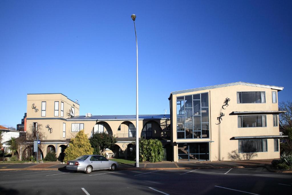 a car parked in a parking lot in front of a building at Ambassador Thermal Motel in Rotorua