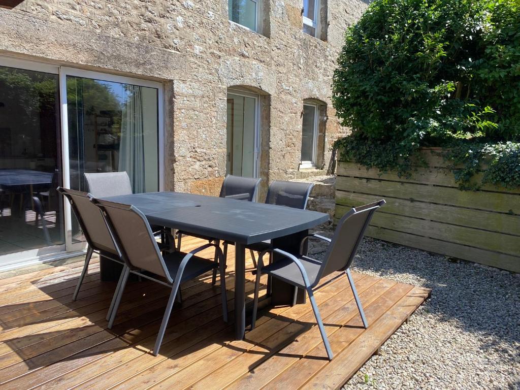 une table et des chaises noires sur une terrasse en bois dans l'établissement La verte Dinannaise, à Quévert