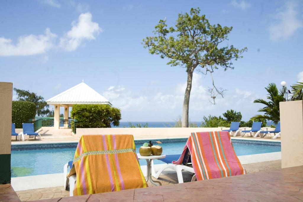 two chairs and a table next to a swimming pool at Cardiff Hotel and Spa in Runaway Bay