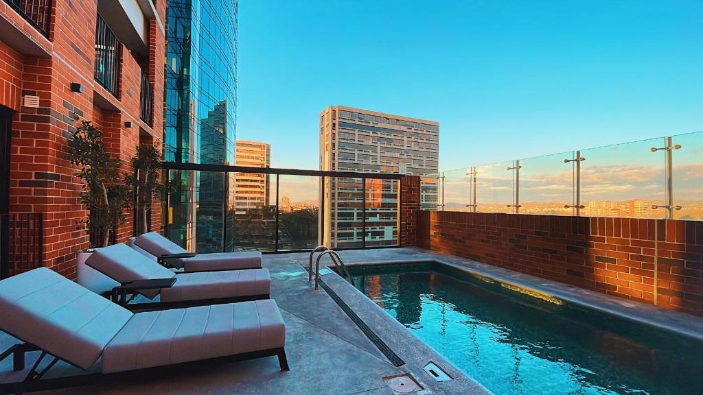 a pool with two chairs and a couch on a building at Airali 1 - Apartamento en el centro - Zona 10 de la Ciudad de Guatemala in Guatemala