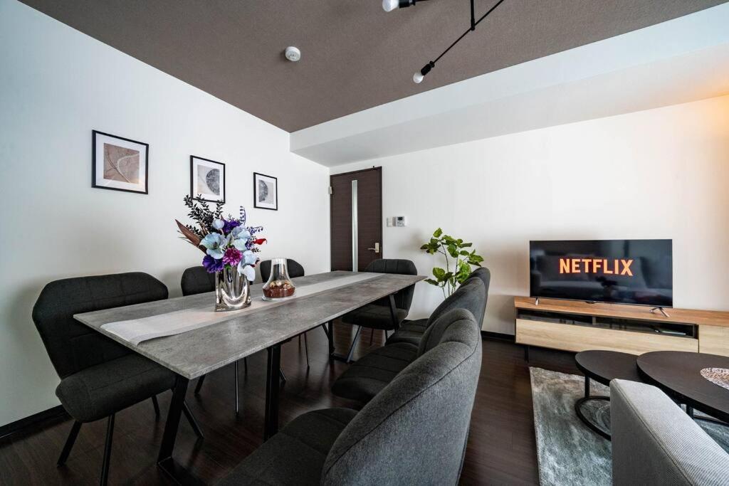 a living room with a table and chairs and a tv at Norwegian Wood in Kita-sanjō
