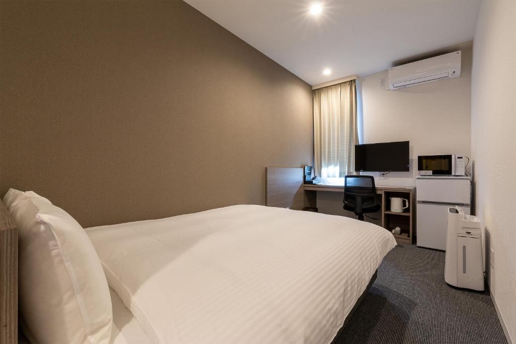 a bedroom with a bed and a desk with a computer at HOTEL R9 Kujukuri "ex Casual Resort COFF Ichinomiya" in Ichinomiya