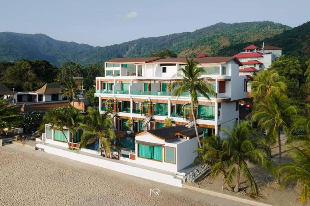 ein großes weißes Gebäude am Strand mit Palmen in der Unterkunft Hotel Villa AoKhanom Beachfront in Khanom