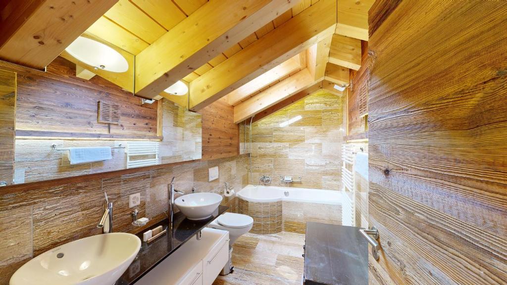 a bathroom with a sink and a toilet and a tub at Luxury Chalets & Apartments by Mountain Exposure in Zermatt