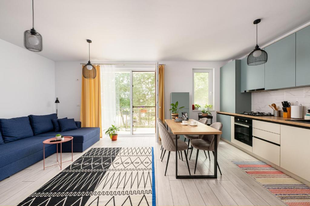 a kitchen and a living room with a blue couch at A&A Luxury Apartment in Giroc
