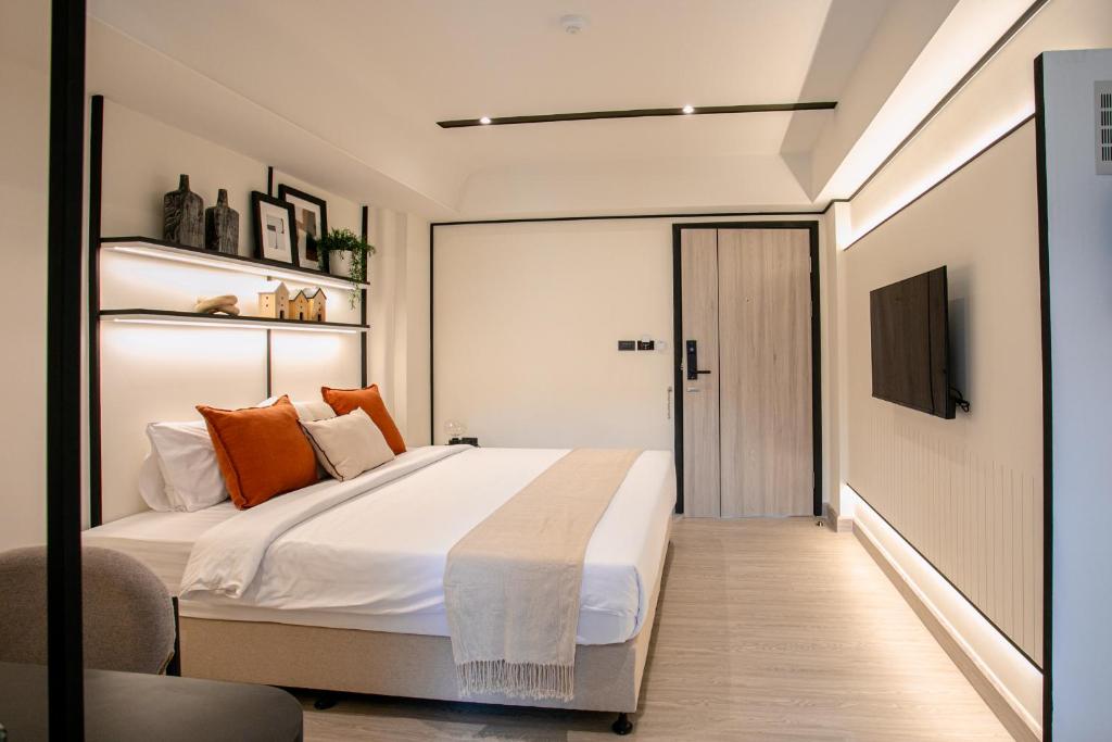 A modern bedroom with a large bed, wall-mounted television and built-in shelving.