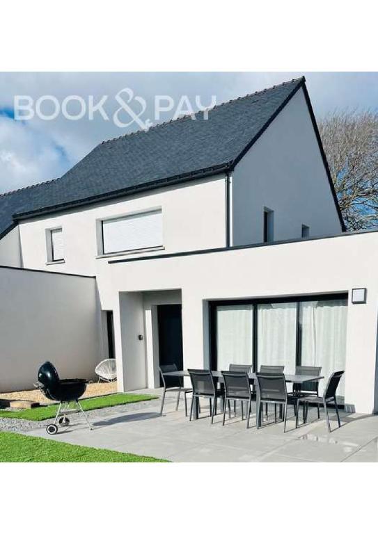 une maison blanche avec une table et des chaises devant elle dans l'établissement Le Ter - Maison avec grand jardin, 5mn de la plage, à Ploemeur