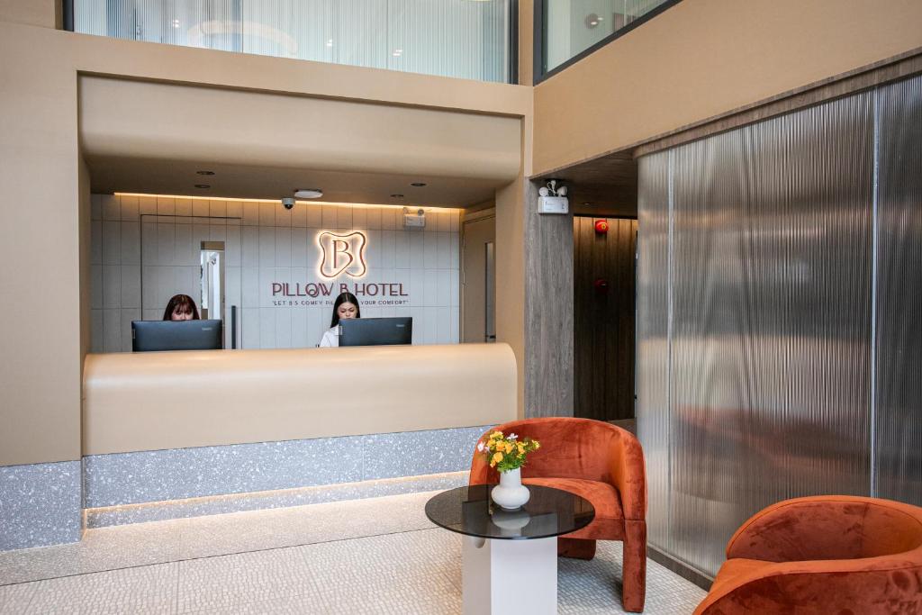 A reception desk backed by the hotel logo, with two lounge chairs in front.
