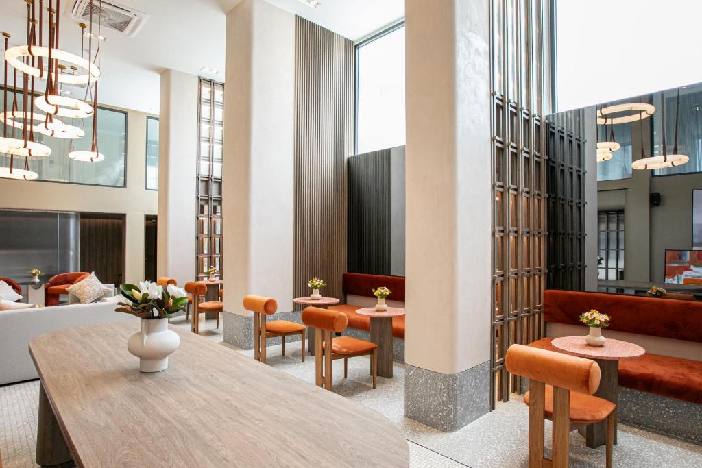 A bright lobby seating area combines a communal table, armchairs and orange banquette seating.