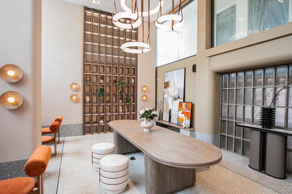 A communal lobby table set beneath sculptural pendant lights and a tall decorative screen.