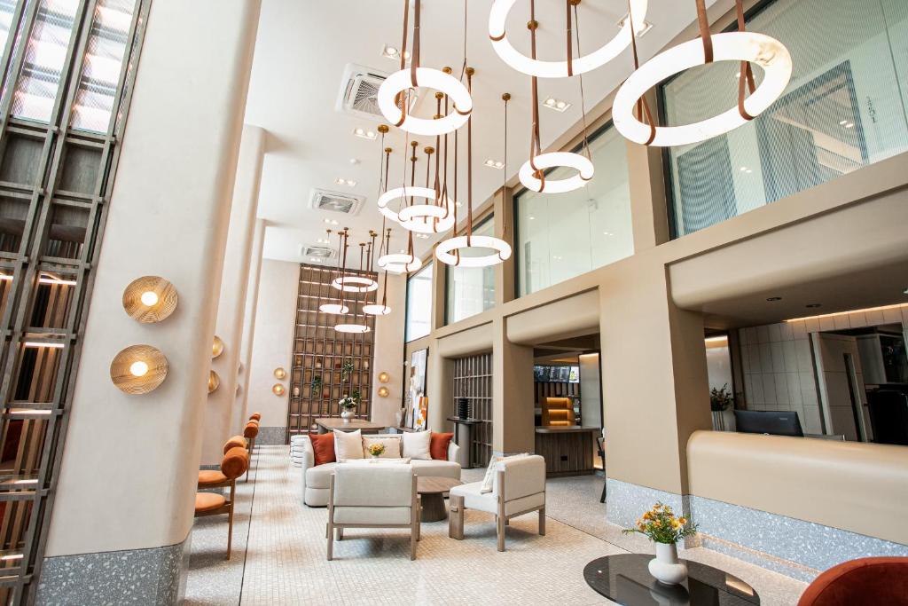 The double-height lobby has lounge chairs, a long seating area and a wall of circular lights.