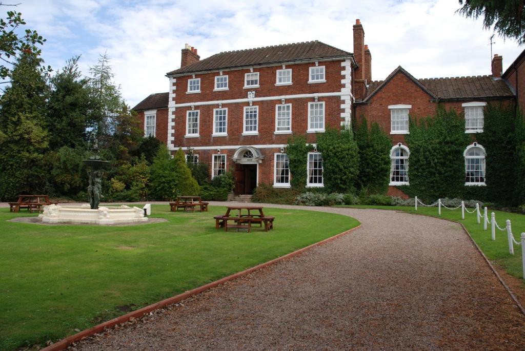 um grande edifício de tijolos com uma mesa de piquenique em frente em Park House Hotel em Shifnal