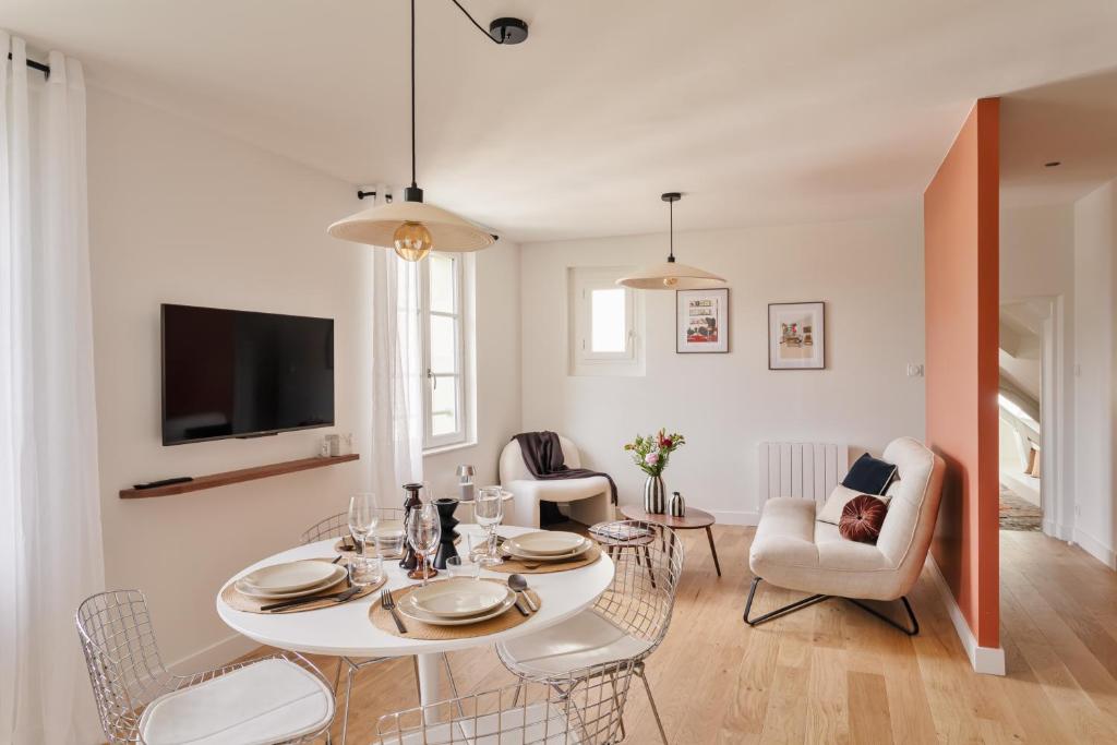 - un salon avec une table, des chaises et une télévision dans l'établissement Le Perchoir - Appt Rennes parking privé, à Rennes