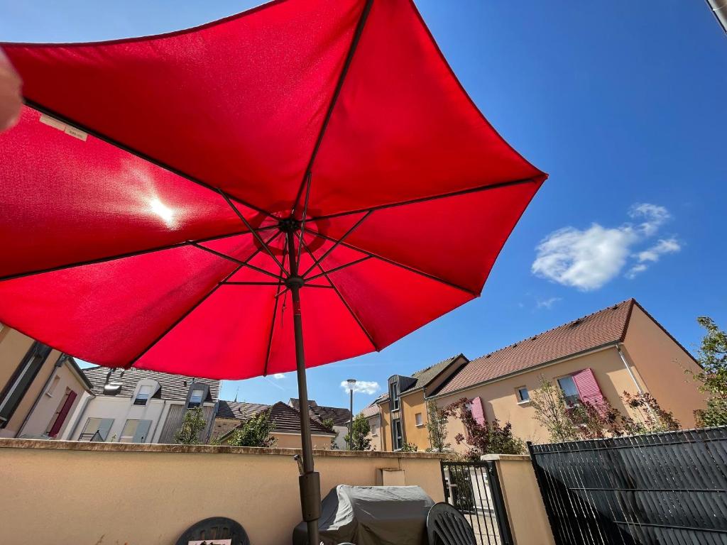 a red umbrella sitting in front of a building at Le cocon du centre ville in Torcy