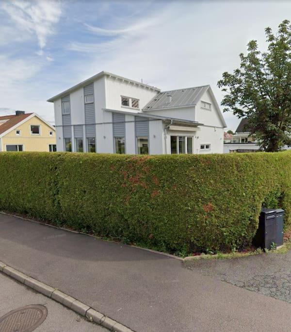 a hedge in front of a white house at Modern villa i Sävedalen in Gothenburg