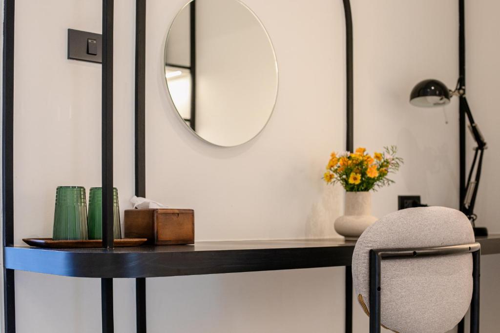A slim wall-mounted desk with a round mirror and upholstered chair.