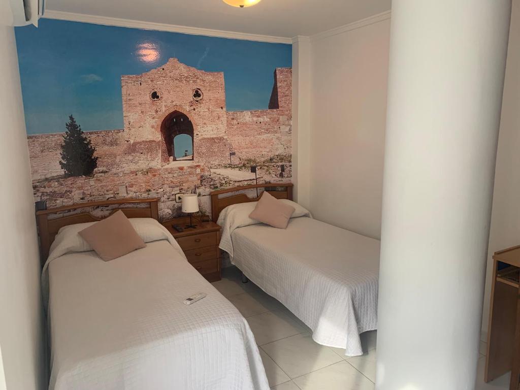 2 camas en una habitación con un edificio en Habitación doble Puerta de Almenara - Alquiler de temporada, en Puerto Sagunto