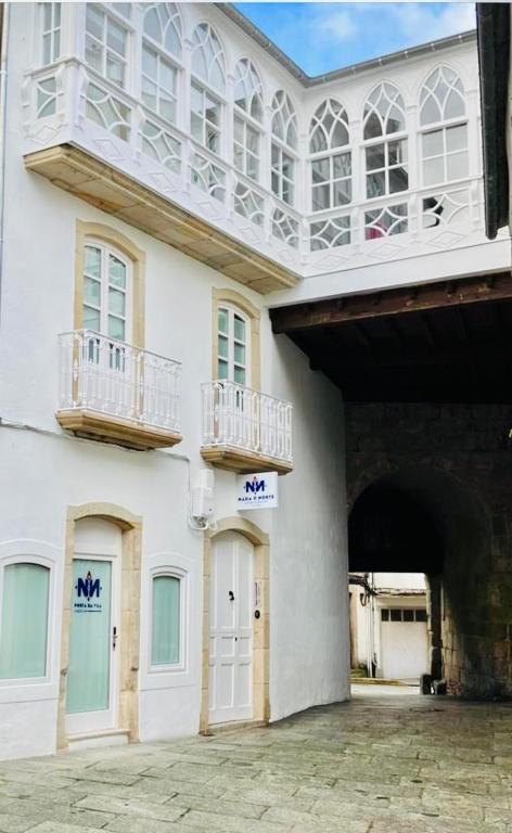 a large white building with two balconies on it at APARTAMENTOS NADA Ó NORTE Centro in Viveiro
