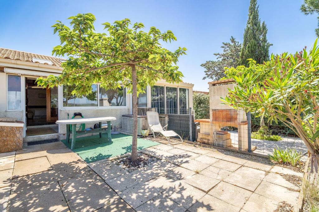 een patio met een tafel en een boom bij Les Eaux Vives 1 in Fleury