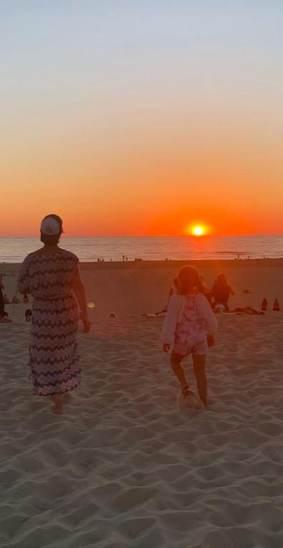 un homme et un enfant courant sur la plage au coucher du soleil dans l'établissement Mobil Home Contis Plage, à Saint-Julien-en-Born