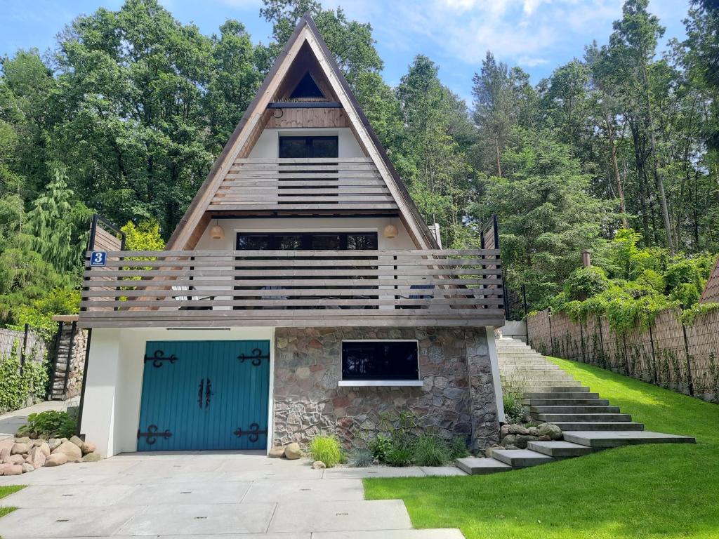 a house with a peaked roof and a blue garage at Dom nad Jeziorem Bory Tucholskie Pomost Łódka in Cierplewo