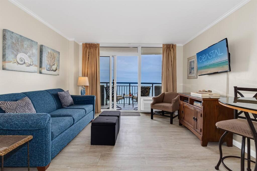 a living room with a blue couch and a view of the ocean at WINTER RATES! Ready Set and Relax, Oceanfront Suite w Jetted tub! B 1134 in Myrtle Beach