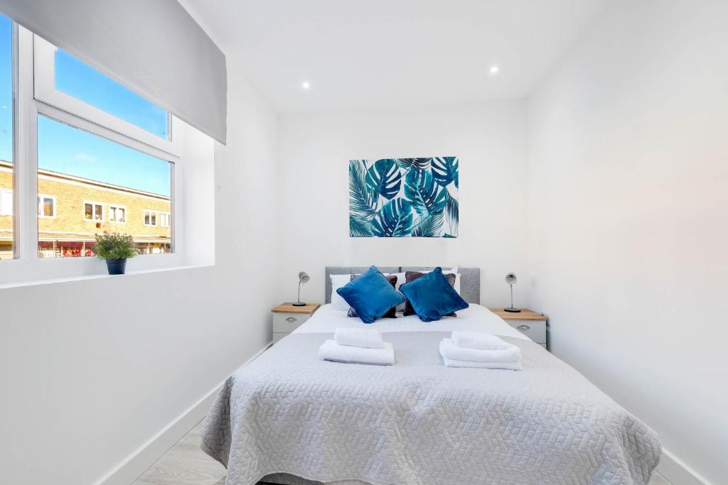 ein weißes Schlafzimmer mit einem großen Bett mit blauen Kissen in der Unterkunft Corby Town Centre Serviced Apartments in Corby