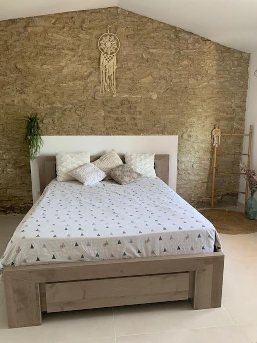 Ce lit se trouve dans une chambre dotée d'un mur en pierre. dans l'établissement Maison de vacances toute équipée à 5mn du Pont-du-Gard au Cœur de Sernhac, à Sernhac