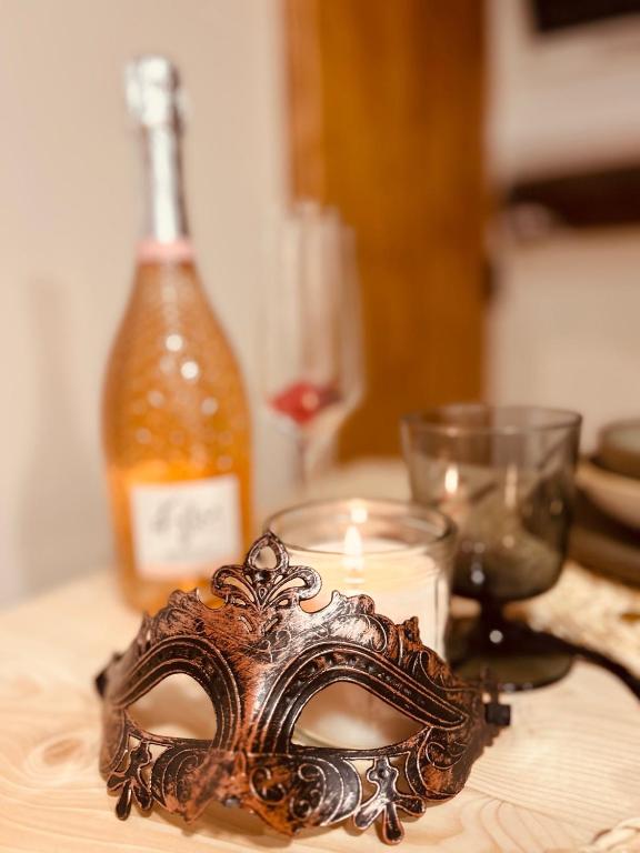 un masque sur une table avec une bougie et une bouteille dans l'établissement Love Room 'Secret des Combles' Vosges, à Plombières-les-Bains