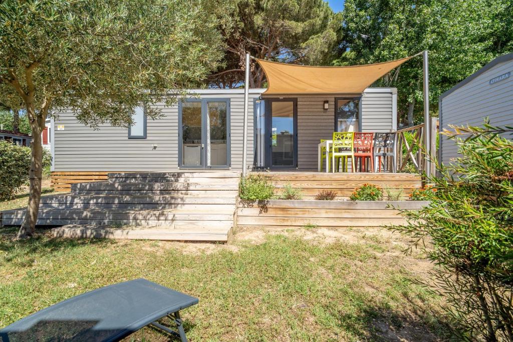 une petite maison avec une terrasse couverte et une tente dans l'établissement Charmant Mobil Home 6 personnes, à Vendres