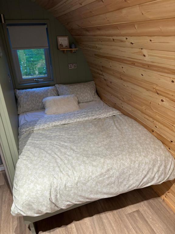 a bed in a room with a wooden wall at Knockmany View Glamping in Augher