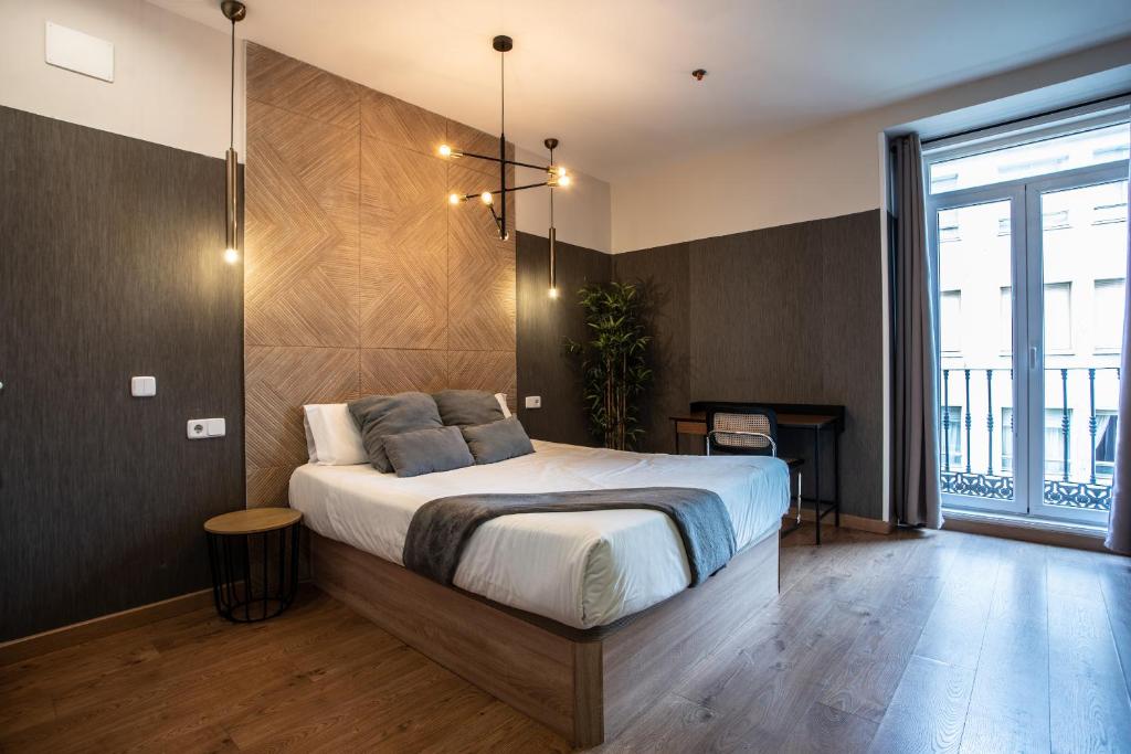 sypialnia z łóżkiem i dużym oknem w obiekcie Suites You Zinc w Madrycie