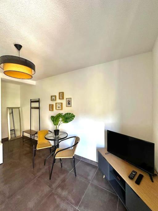 un salon avec une télévision, une table et des chaises dans l'établissement Casa Félix, à Perpignan