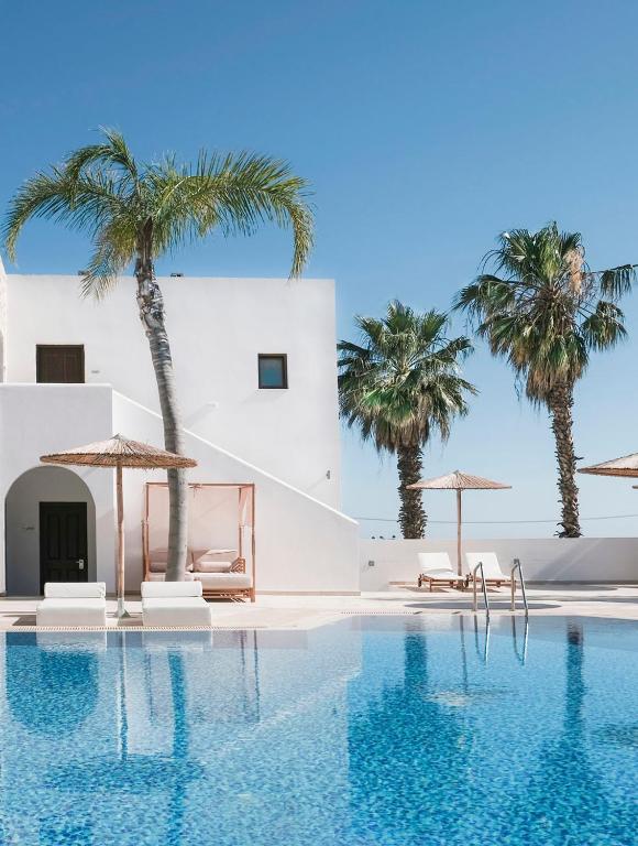 a pool with palm trees and a white building at Costa Lindia Blue Star - Adults Only in Lartos