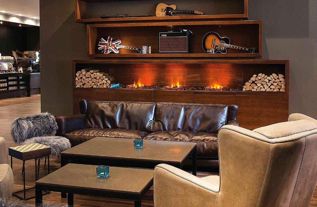 a living room with a leather couch and a fireplace at Motel One Manchester-Piccadilly in Manchester
